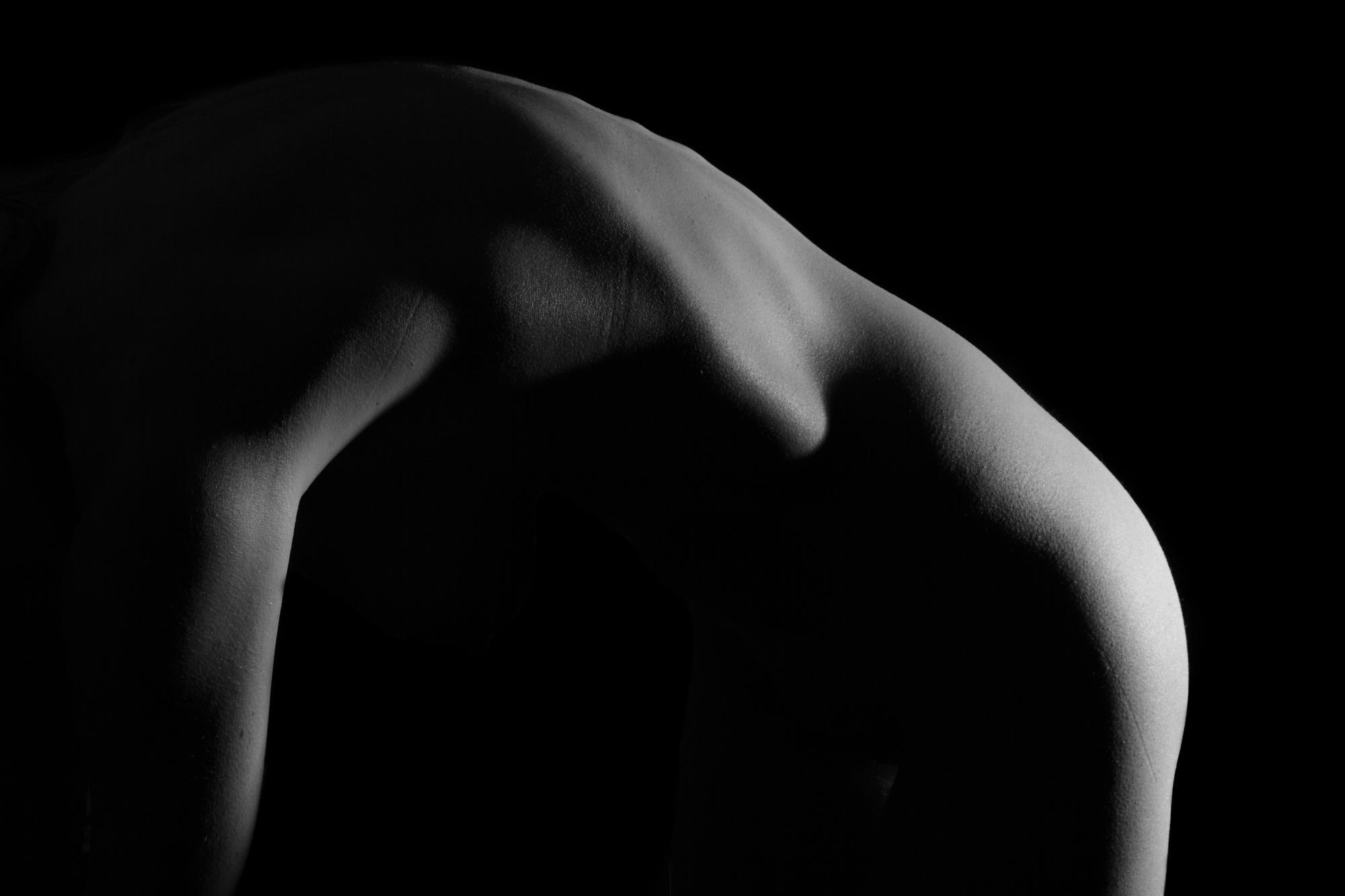 The arch is an abstract view of the human form. The arch is covered in shadow and is brightly lit from the right. The straight structure on the left side of the image is juxtaposed by the soft rounded structure on the right side of the image.